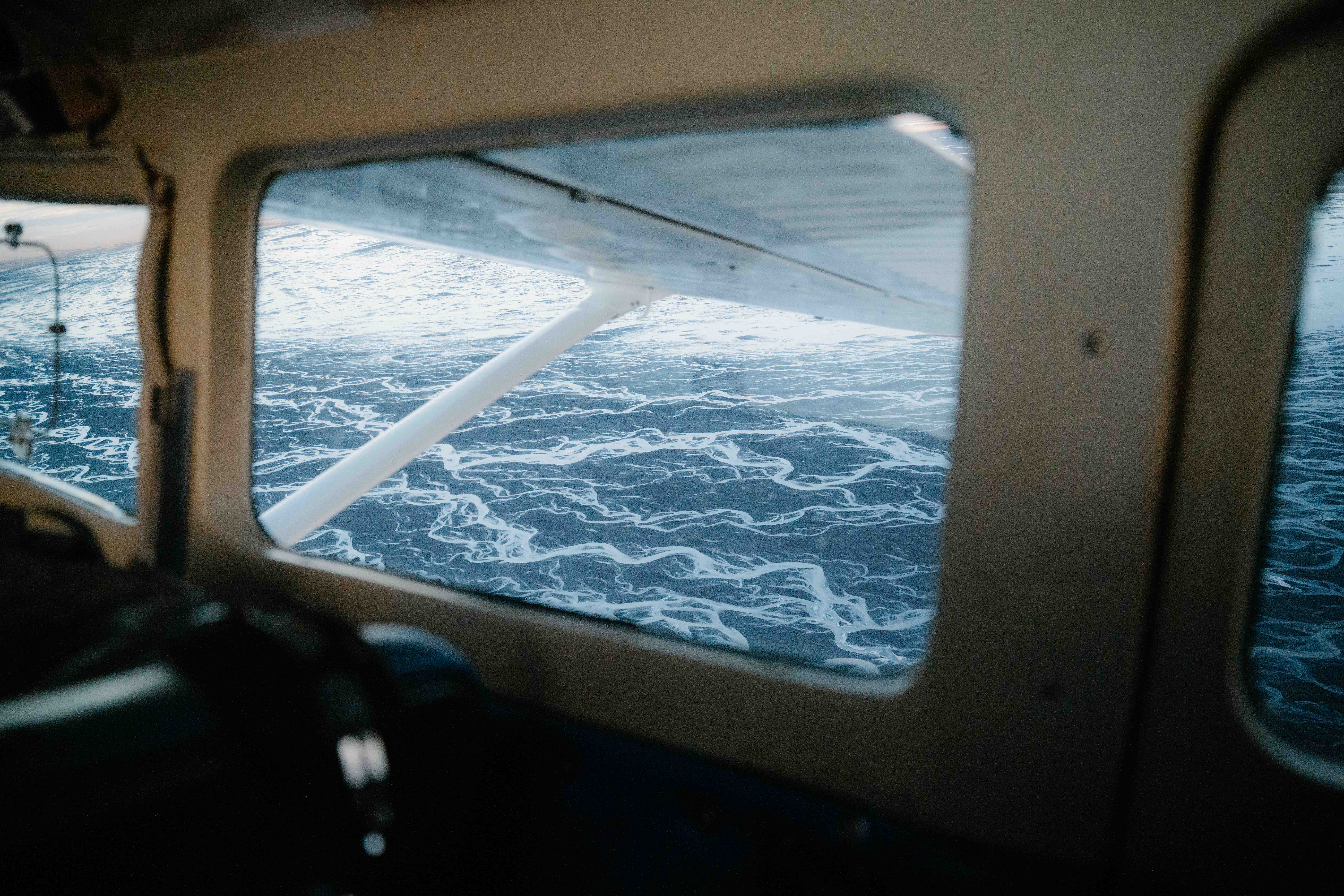 A view of the ocean through the window of a small aeroplane